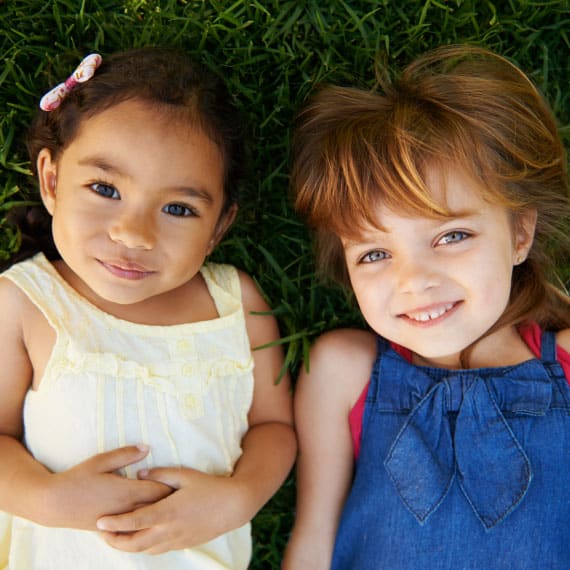 Preschool-aged girls laying in the grass