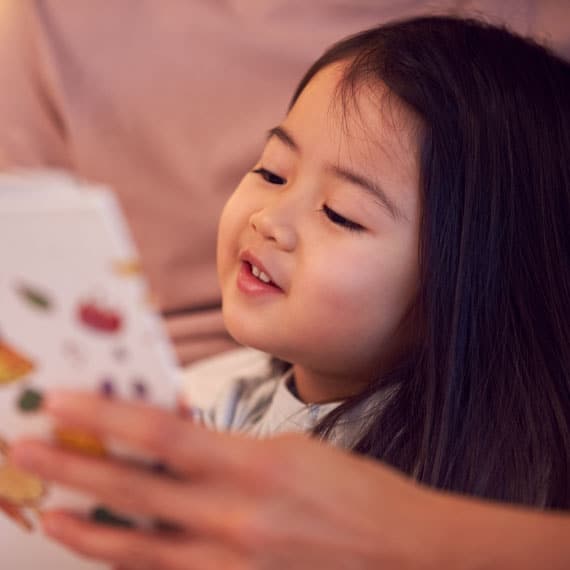 Preschool child reading with caregiver